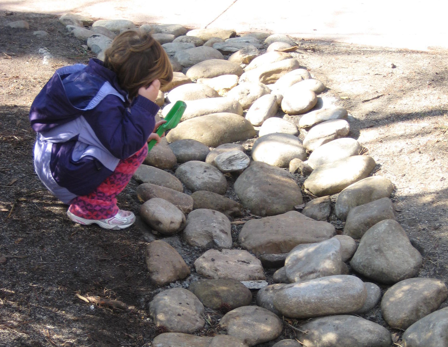 child inspecting stones in a dry creek bed
