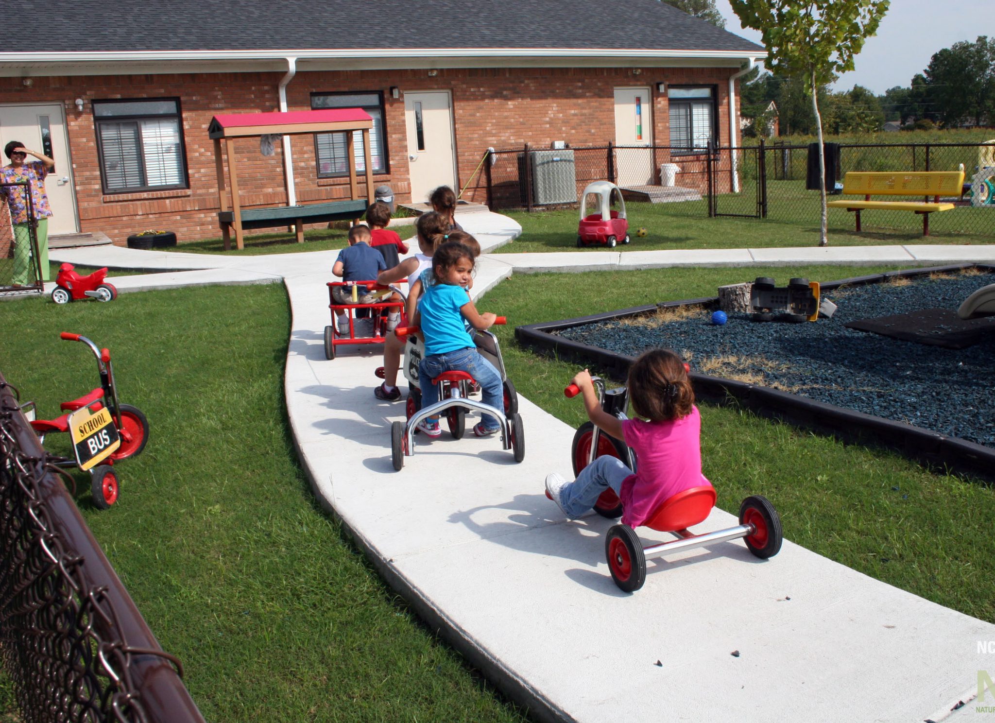 after renovation showing children engaging in wheeled toy play on newly installed pathway