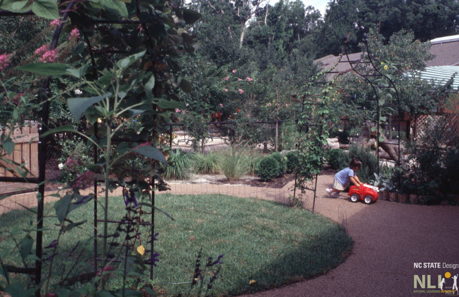 child playing with wheeled toy on pathway