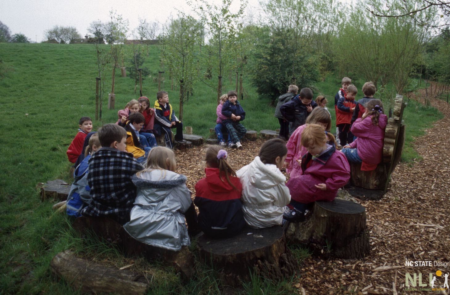 children sitting around a log circle