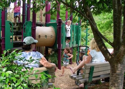 children playing on play equipment with adults overseeing