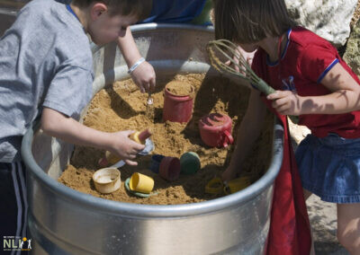 children engaging in mud play in barrels