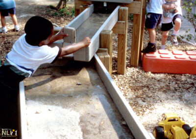 children engaging in water play with raised troughs
