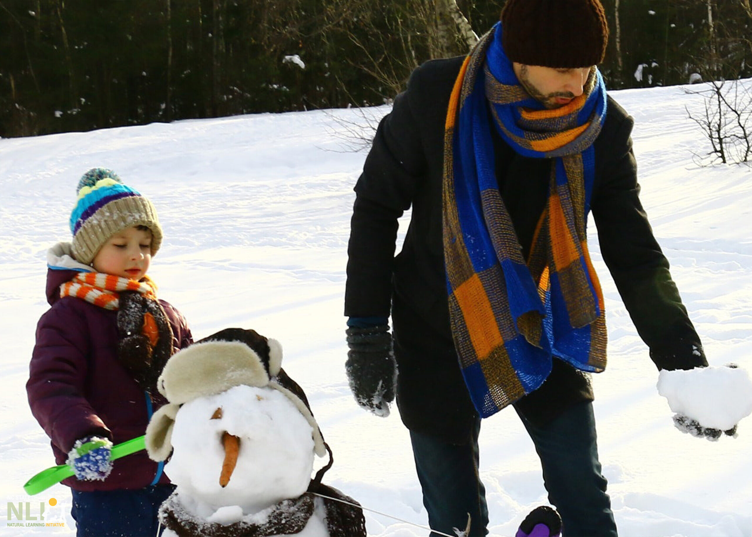 parent and child building a snowman