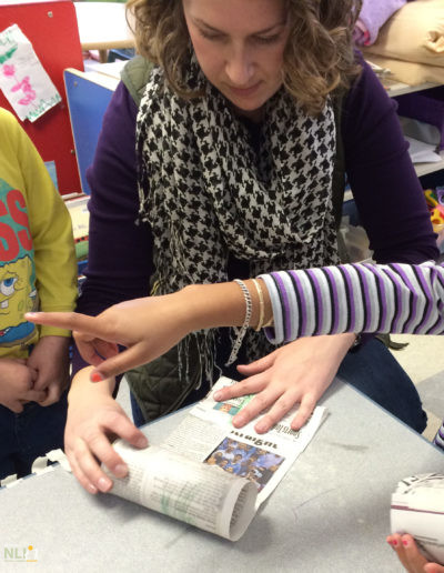 adult helping children roll newspaper strips