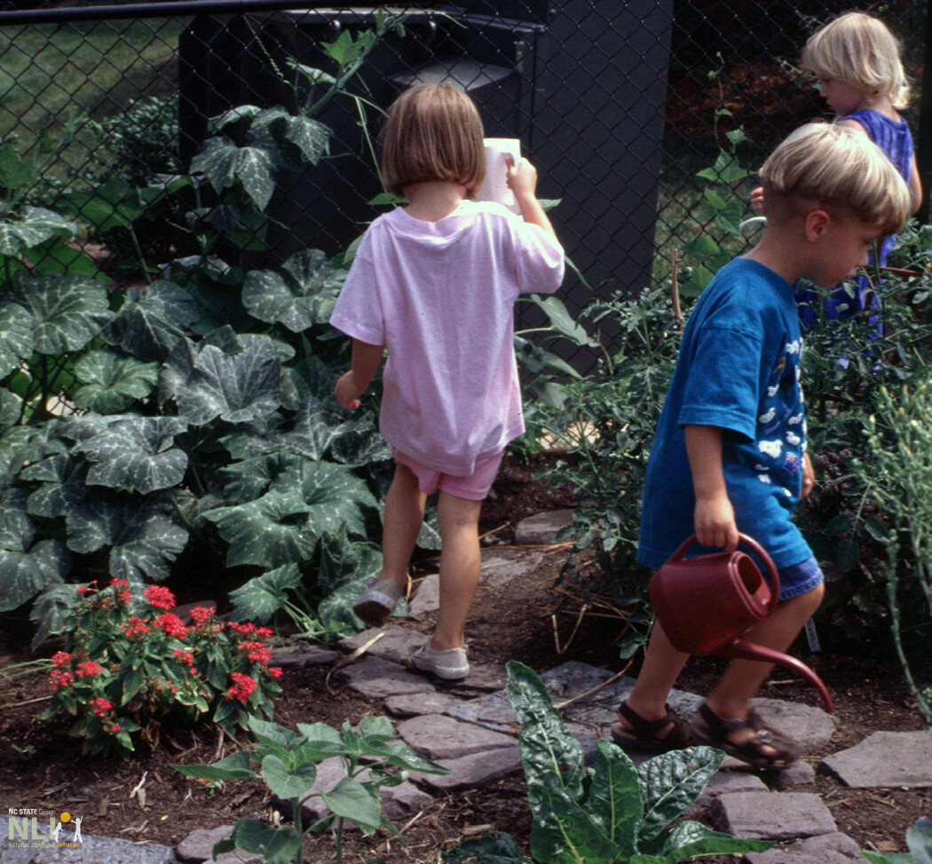 children in a garden watering plants