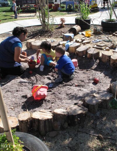teacher engaging with children in dirt play
