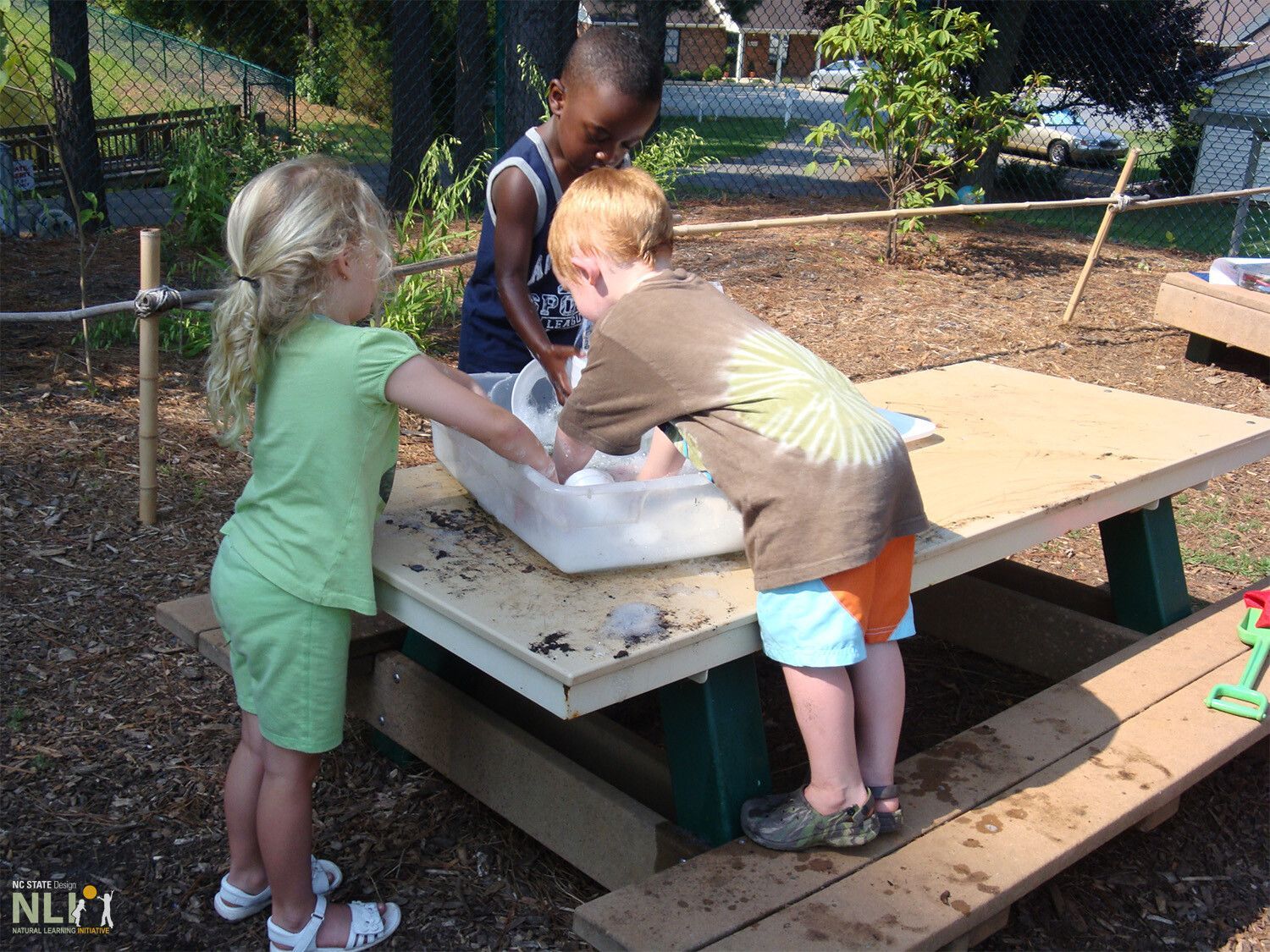 children engaging in water play in a plastic container