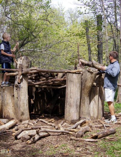adult and child constructing a log fort