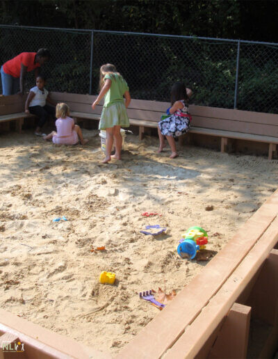 children in a sand play setting with built in benches
