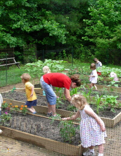 children and caregiver in a raised bed garden