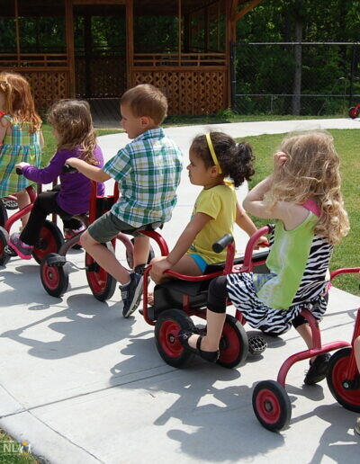 children on wheeled toys on a concrete pathway