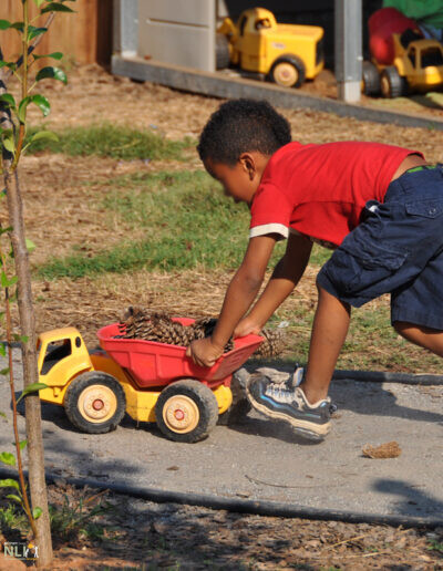 child using a wheeled toy on pathway