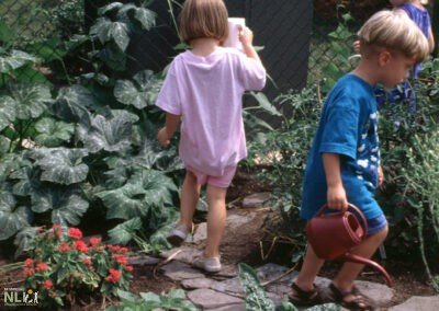 child watering plants in walk-in garden