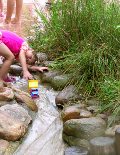 child playing in a hard-surfaced stream